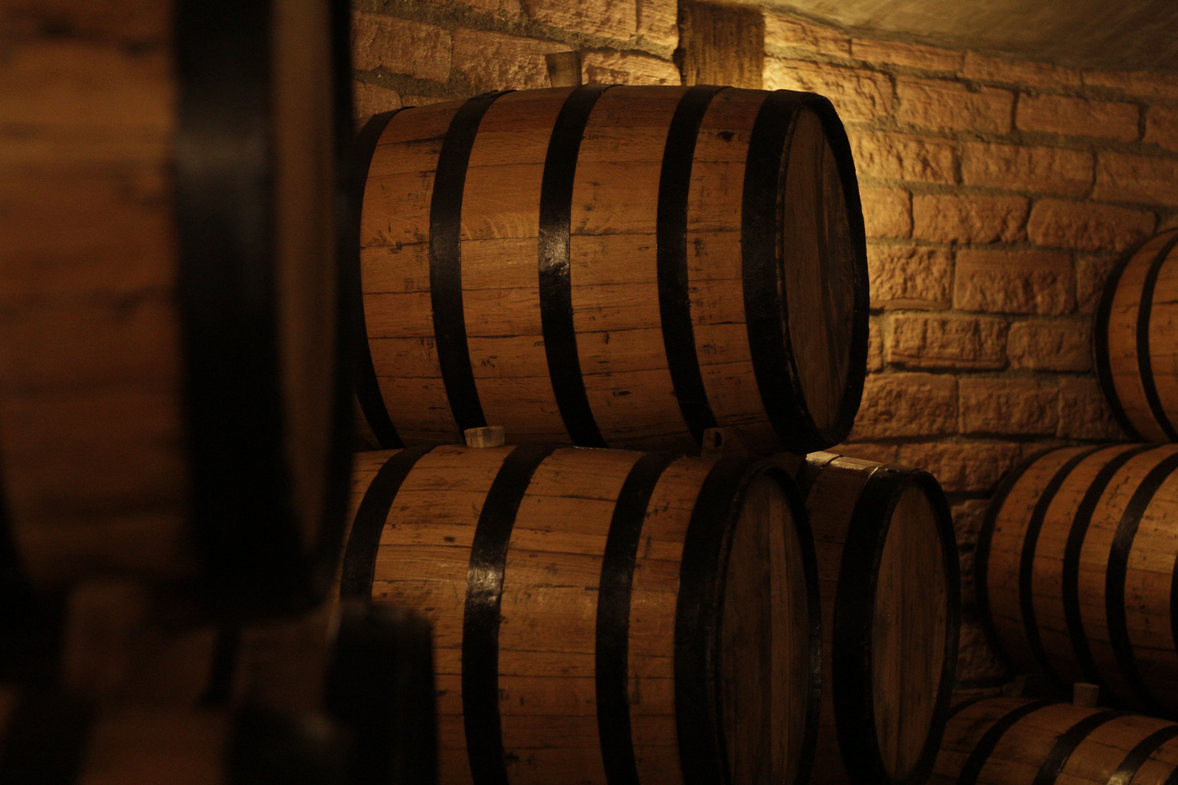 Oak whiskey barrels aging in a warm candlelit cellar